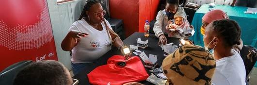 Group of South Africans sit at a table leaning how to use their Watts of Love solar-powered lights